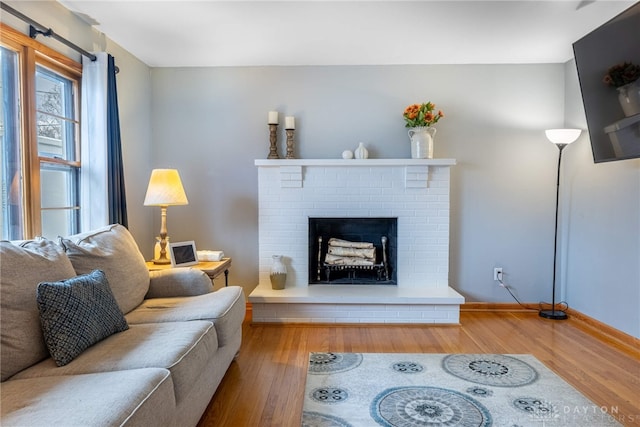 living room with a fireplace, baseboards, and wood finished floors