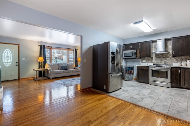 kitchen with wall chimney exhaust hood, stainless steel appliances, light countertops, and light wood-style flooring