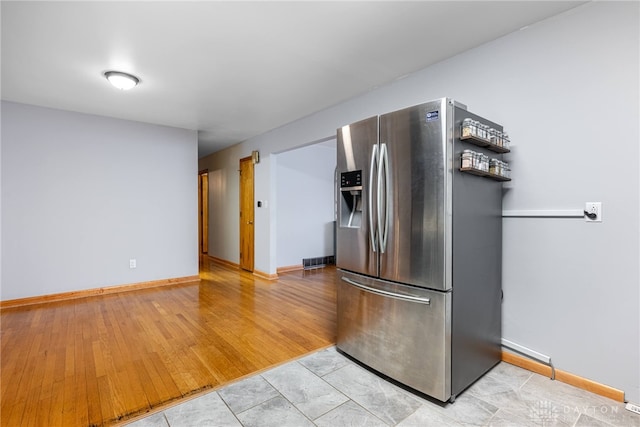 kitchen with baseboards, stainless steel refrigerator with ice dispenser, visible vents, and light wood-style floors