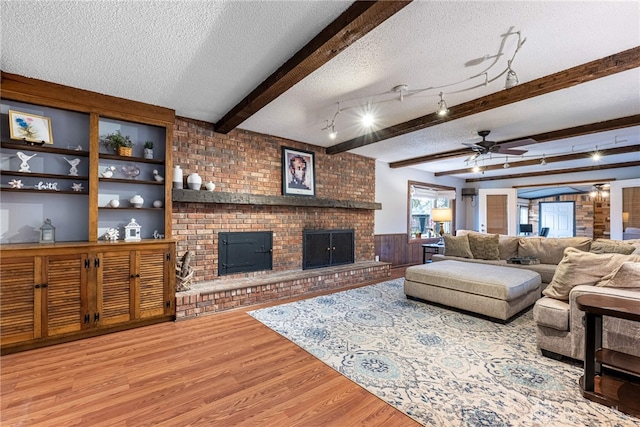 living room featuring a textured ceiling, a fireplace, wood finished floors, and beam ceiling