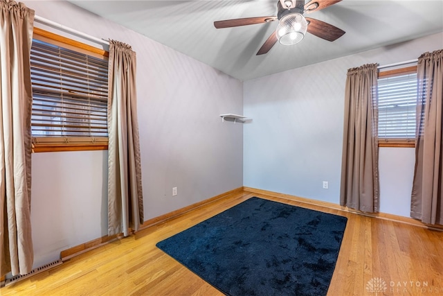 empty room with a ceiling fan, visible vents, baseboards, and wood finished floors