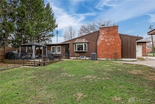 view of front facade with a chimney, a gazebo, central AC unit, a front yard, and fence