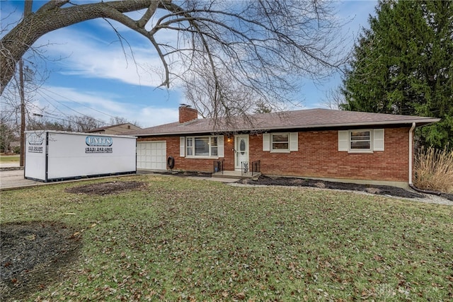 single story home featuring an attached garage, a chimney, a front lawn, and brick siding