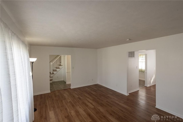 spare room with baseboards, stairway, and wood finished floors