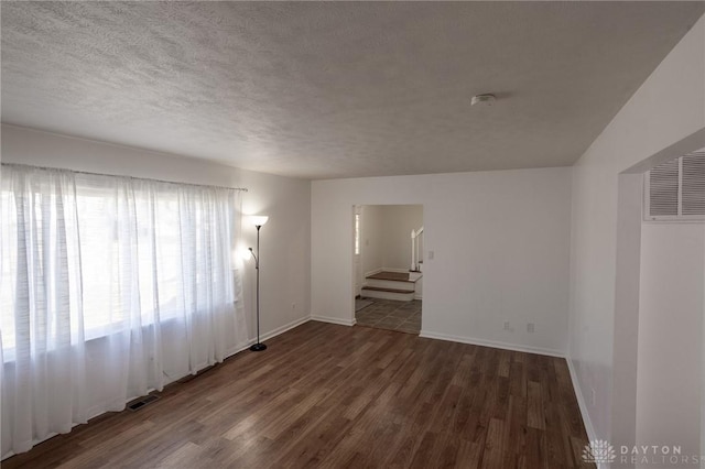 spare room with a textured ceiling, stairs, visible vents, and wood finished floors