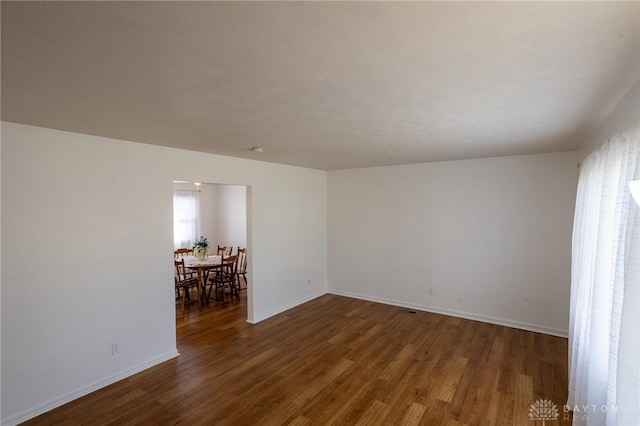 spare room featuring baseboards and wood finished floors