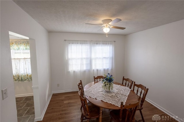 dining area featuring ceiling fan, a textured ceiling, baseboards, and wood finished floors