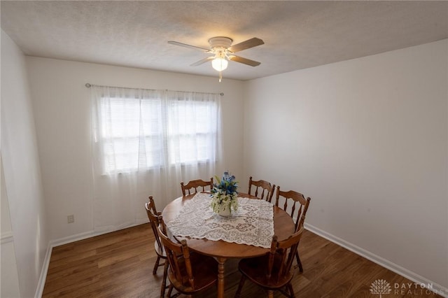 dining area featuring a textured ceiling, wood finished floors, a ceiling fan, and baseboards