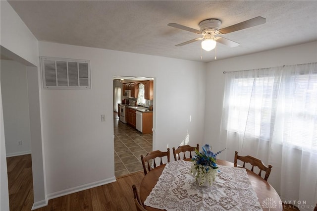 dining space with visible vents, ceiling fan, a textured ceiling, wood finished floors, and baseboards