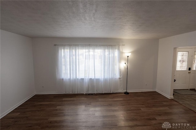 interior space featuring a textured ceiling, baseboards, and wood finished floors