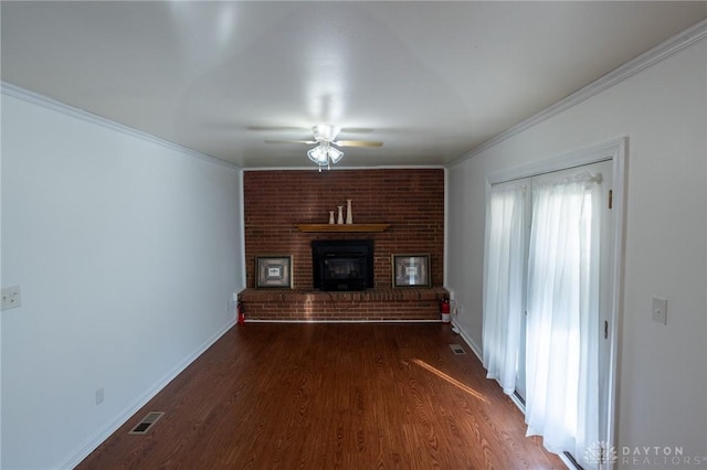 unfurnished living room with ceiling fan, dark wood-style flooring, baseboards, ornamental molding, and a brick fireplace