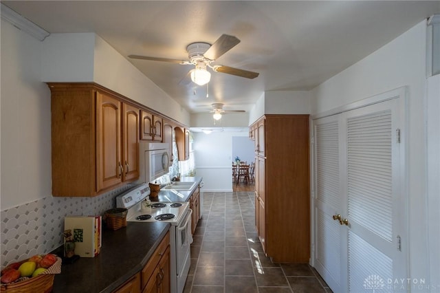 kitchen featuring dark tile patterned flooring, white appliances, brown cabinetry, and dark countertops