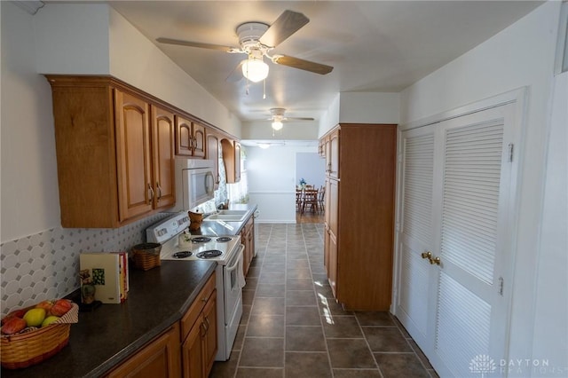 kitchen featuring brown cabinetry, white appliances, dark tile patterned floors, and backsplash