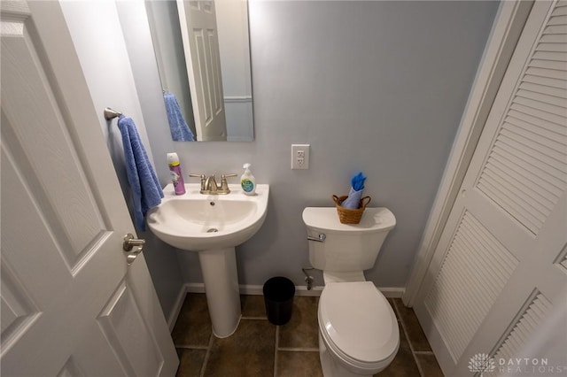 half bathroom with baseboards, toilet, and tile patterned floors