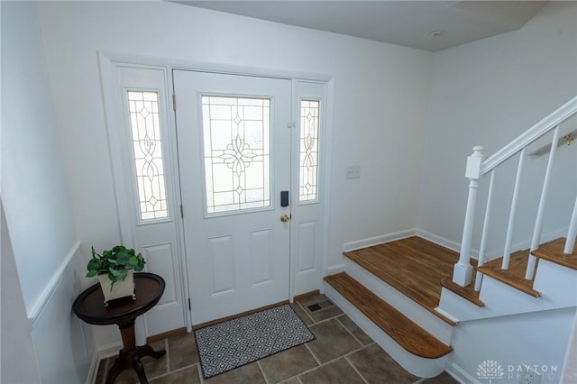 foyer featuring a healthy amount of sunlight, baseboards, and stairway