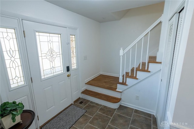 entryway featuring a healthy amount of sunlight, stairs, baseboards, and dark tile patterned flooring