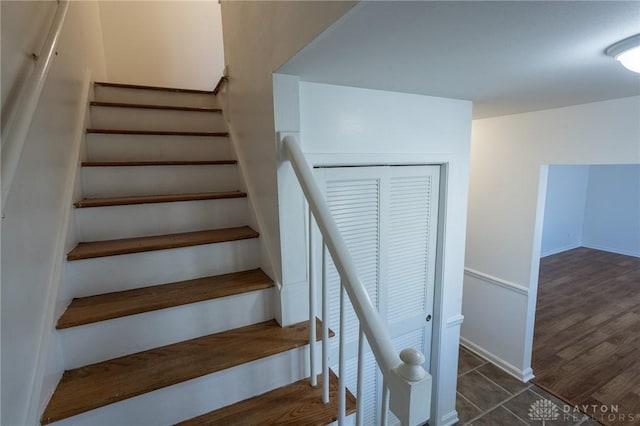 staircase featuring wood finished floors and baseboards