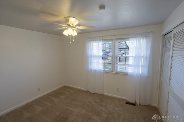 spare room featuring light carpet, ceiling fan, visible vents, and baseboards