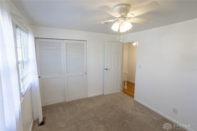 unfurnished bedroom featuring carpet, a closet, visible vents, ceiling fan, and baseboards