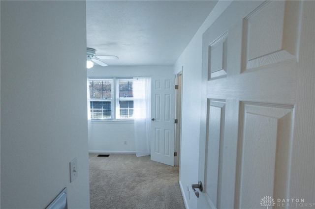 hallway featuring carpet flooring, visible vents, and baseboards