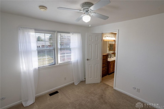 unfurnished bedroom featuring light colored carpet, visible vents, connected bathroom, and baseboards