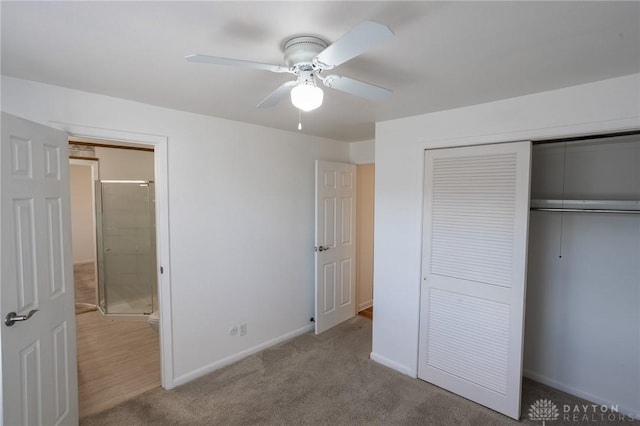 unfurnished bedroom featuring a closet, ensuite bathroom, a ceiling fan, carpet flooring, and baseboards