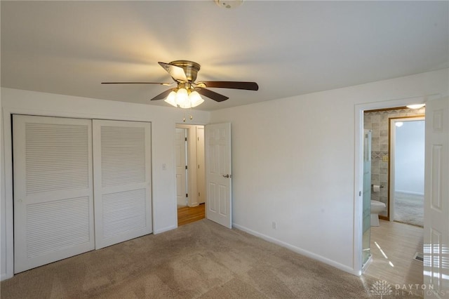 unfurnished bedroom with light colored carpet, a ceiling fan, baseboards, a closet, and ensuite bath