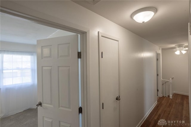 hall featuring wood finished floors, an upstairs landing, and baseboards