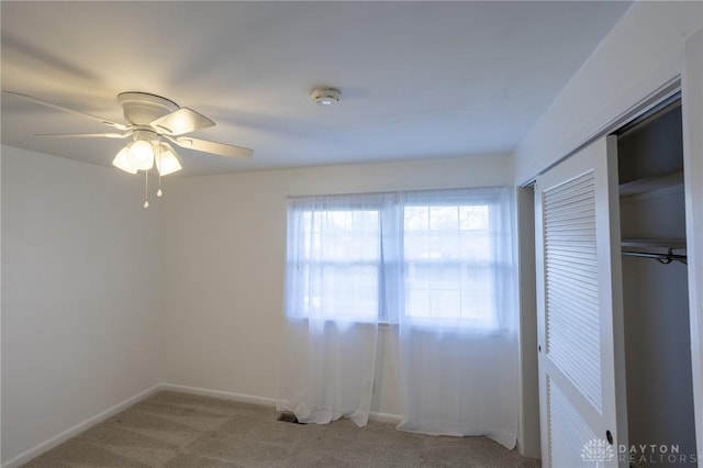 unfurnished bedroom with ceiling fan, carpet floors, a closet, and baseboards