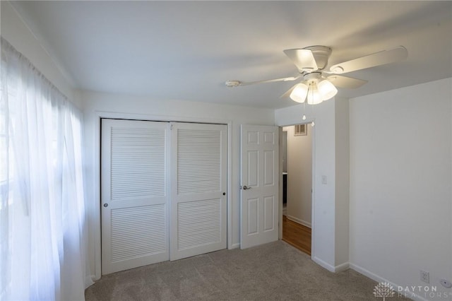 unfurnished bedroom with baseboards, visible vents, a ceiling fan, carpet floors, and a closet