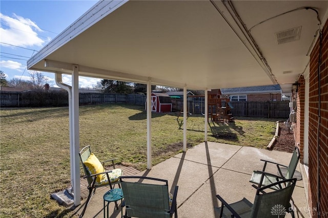 view of patio with a fenced backyard, an outbuilding, a playground, and a shed