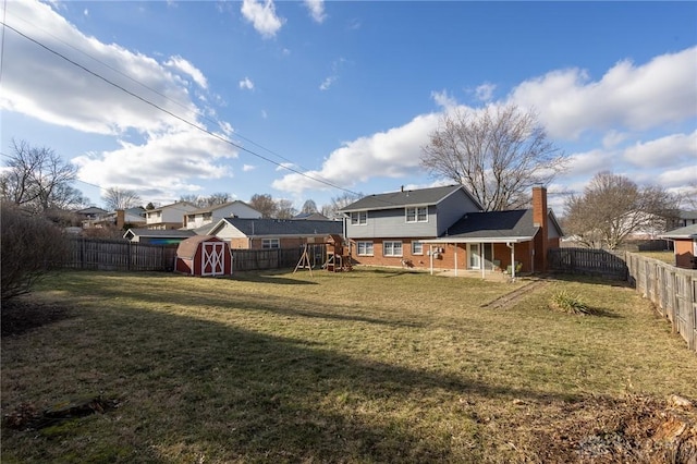 rear view of property featuring a storage unit, a chimney, an outdoor structure, and a fenced backyard