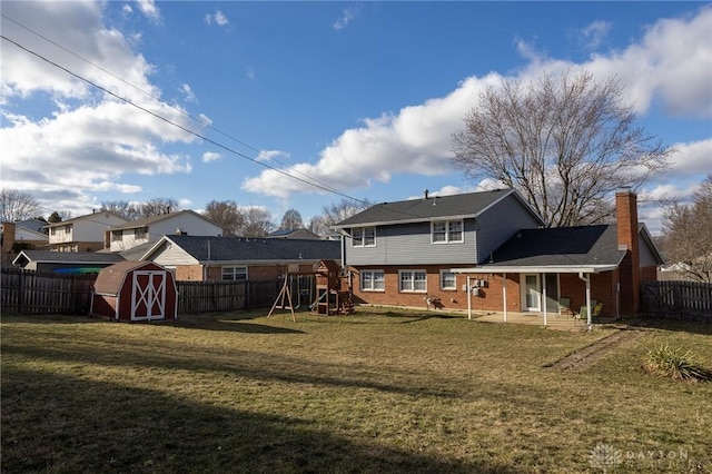 back of property featuring a playground, brick siding, a storage shed, a fenced backyard, and an outdoor structure