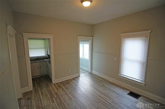 unfurnished bedroom featuring dark wood finished floors, visible vents, a sink, and baseboards