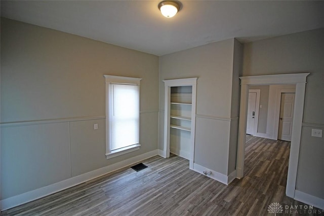 unfurnished room featuring wainscoting, visible vents, and wood finished floors