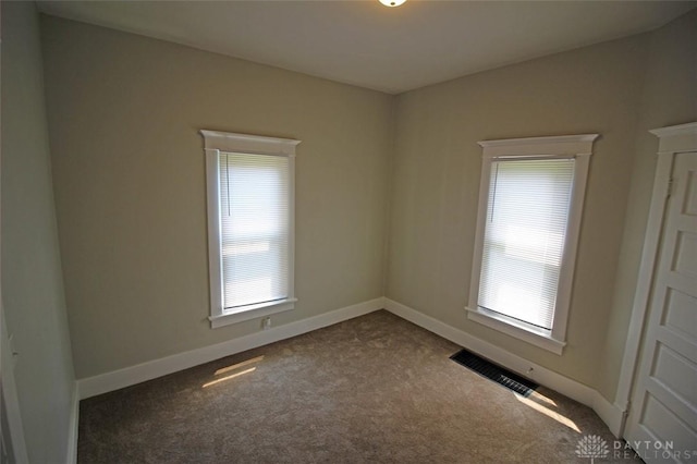 carpeted empty room featuring baseboards and visible vents