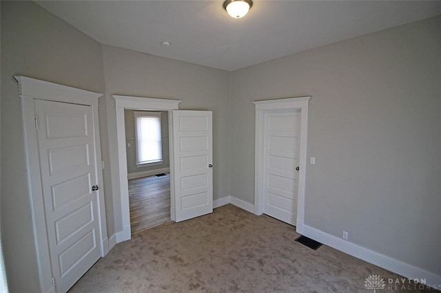 unfurnished bedroom featuring carpet, visible vents, and baseboards