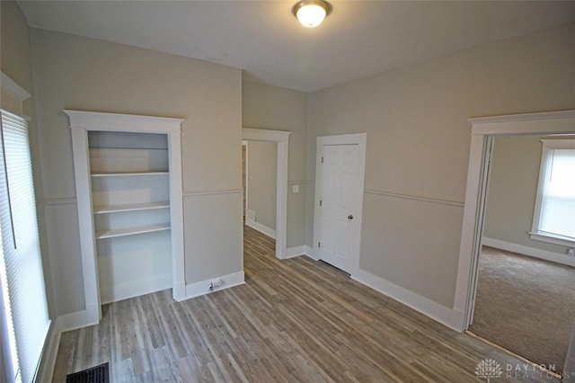 unfurnished bedroom featuring wood finished floors, visible vents, and baseboards