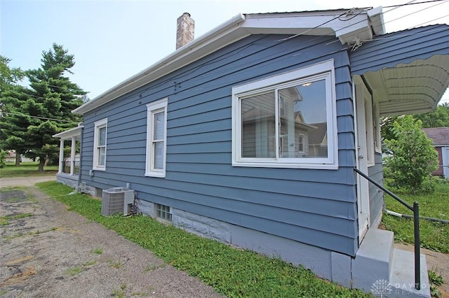 view of side of property with a chimney and central AC unit