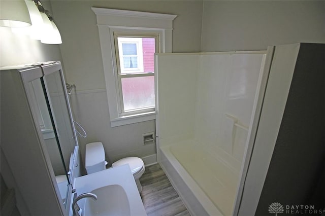 bathroom featuring toilet, tile walls, a sink, and wood finished floors