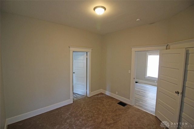 carpeted spare room featuring visible vents and baseboards