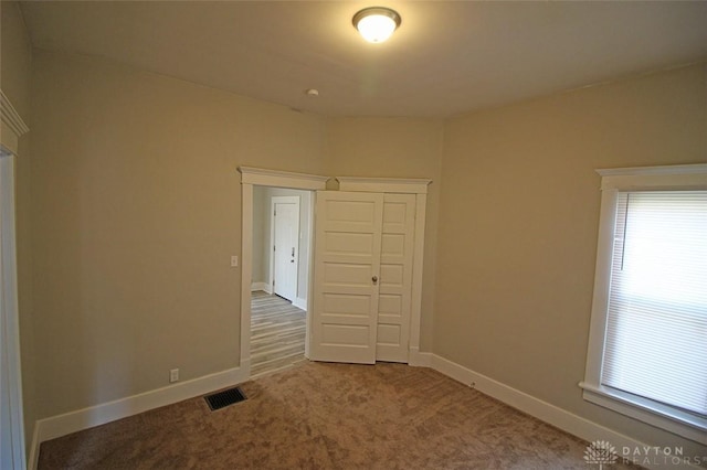 unfurnished room with carpet flooring, visible vents, and baseboards