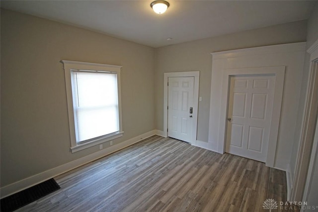 unfurnished room featuring visible vents, baseboards, and wood finished floors