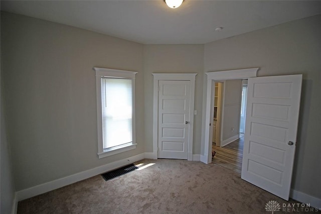 unfurnished bedroom featuring carpet, visible vents, and baseboards