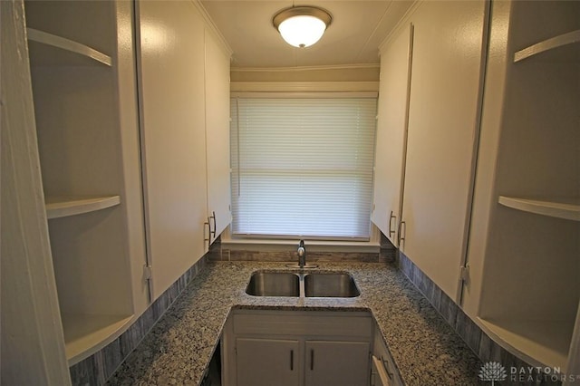 kitchen featuring crown molding, stone counters, a sink, and white cabinets