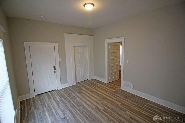 unfurnished room featuring visible vents, baseboards, and wood finished floors