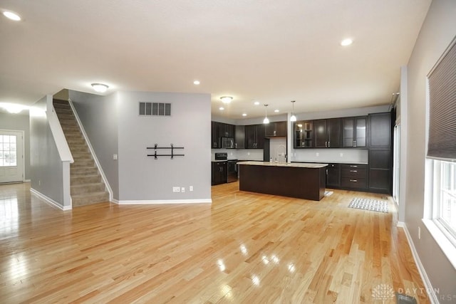 kitchen with light countertops, open floor plan, visible vents, and light wood-style flooring