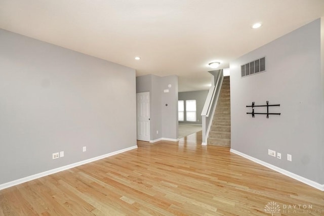 unfurnished room with stairway, baseboards, visible vents, and light wood-style floors