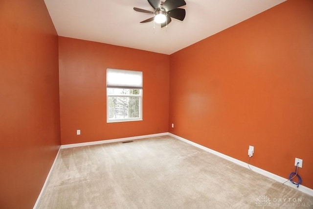 spare room with carpet flooring, ceiling fan, visible vents, and baseboards