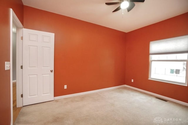 empty room with light carpet, baseboards, visible vents, and a ceiling fan